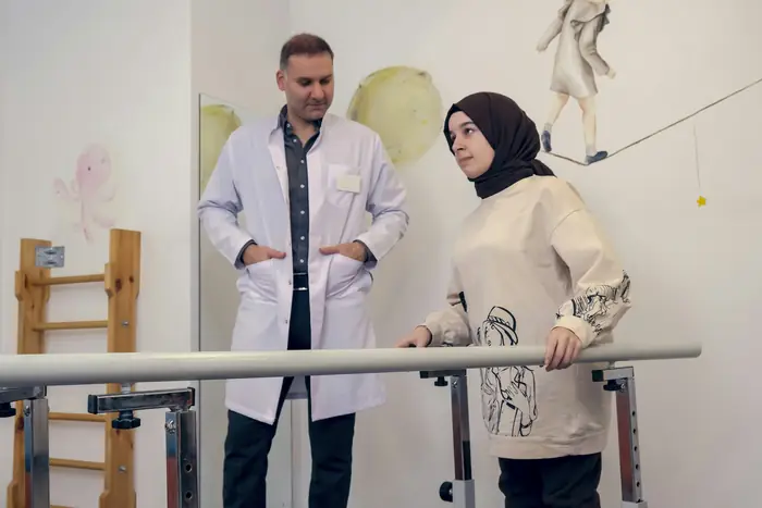 Hekim, paralel bar yanında hastayla konuşuyor