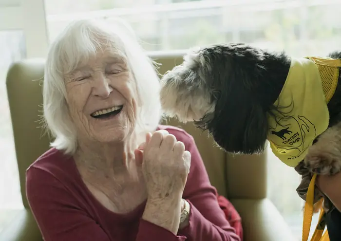 Yaşlı bir kadın evinde köpeğiyle gülüyor