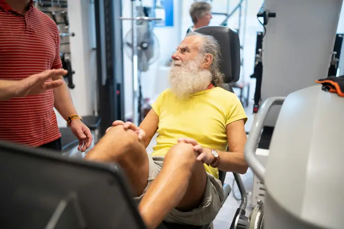 Beyaz sakallı yaşlı bir adam spor salonunda egzersiz yapıyor